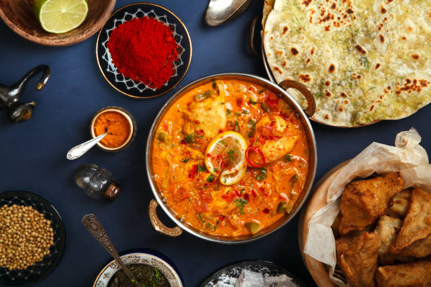 Indian cuisine on diwali holiday: tikka masala, samosa, patties and sweets with mint chutney and spices. Dark blue background